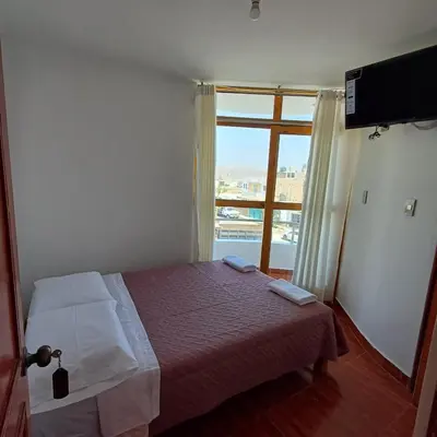 a small bedroom with a bed and a window at El Capricho II Paracas in Paracas