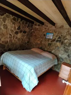 a bedroom with a bed in a stone wall at HOSTEL SAMANA WASI CHAULLAY in Cusco