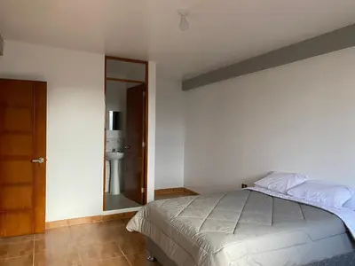 a bedroom with a bed and a bathroom with a mirror at Casa Hospedaje El Trebol in Oxapampa