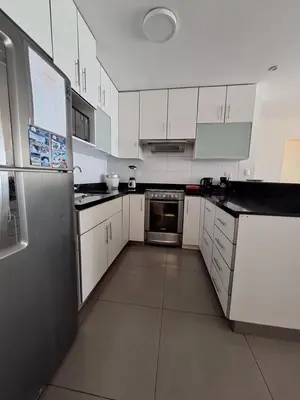 a kitchen with white cabinets and a stainless steel refrigerator at Nuevo Paracas Apartment in Paracas