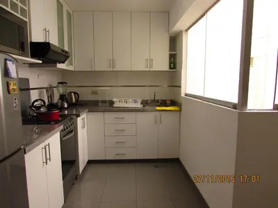 a small kitchen with white cabinets and a window at Bonito Apartamento en Miraflores in Lima