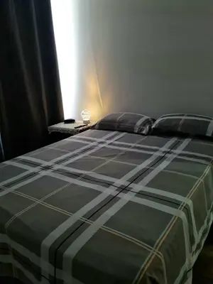 a bed with a black and white comforter in a bedroom at Dormitorio matrimonial 02 in Lima
