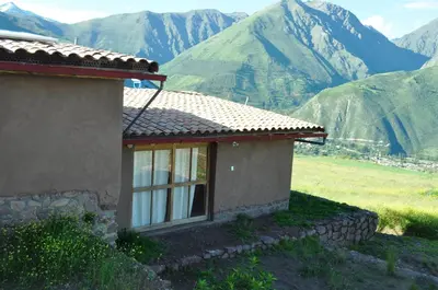 a small house with mountains in the background at Pampachayoq - Mountain retreat in Urubamba