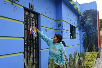 a woman standing in front of a blue building holding a kite at Casita Libertad Barranco in Lima