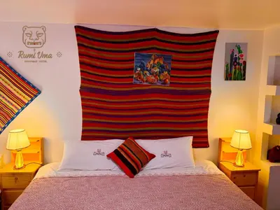 a bedroom with a bed with a striped wall at RumiUma Boutique Hotel in Cusco