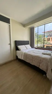 a bedroom with a large bed and a large window at La Herencia - Oxapampa in Oxapampa