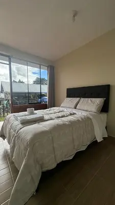 a bedroom with a large bed with a large window at La Herencia - Oxapampa in Oxapampa
