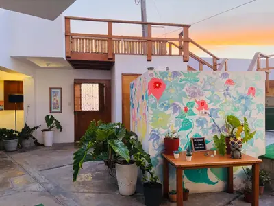 a room with a table and a balcony with plants at El Templo Surf House in Punta Hermosa