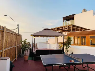 a patio with a table and an umbrella at El Templo Surf House in Punta Hermosa