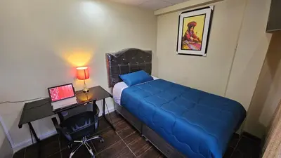 a bedroom with a bed and a desk with a laptop at Casa Independiente cerca al Centro en Segundo Piso - Los Profesionales in Cusco
