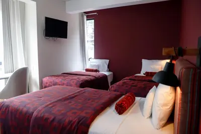 a hotel room with two beds and a television at Mamasara Machupicchu in Machu Picchu