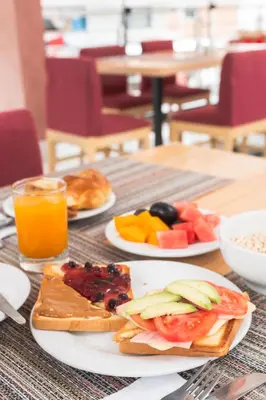 a table with two plates of food and orange juice at Mamasara Machupicchu in Machu Picchu