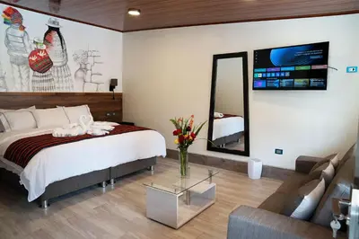 a bedroom with a bed and a couch and a mirror at Hotel Tierra Inka Sacred Valley in Ollantaytambo