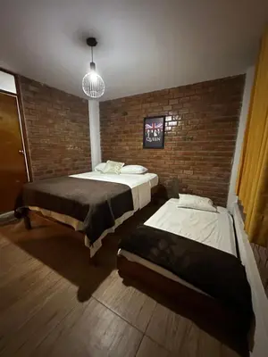 a bedroom with two beds and a brick wall at La Fogata del Sur in Fundo Copacabana