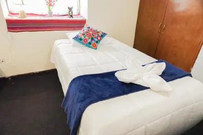 a bedroom with a white bed with a bow on it at WARM AND CENTRAL HOUSE WITH SPECTACULAR VIEW OF CUSCO in Cusco