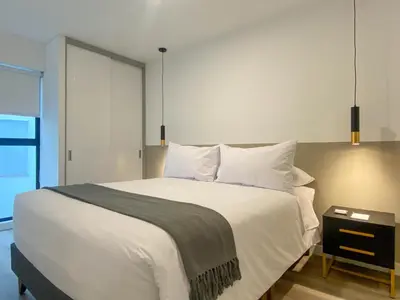 a bedroom with a large white bed and a table at Alameda by Wynwood House in Lima