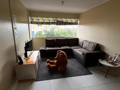 a teddy bear sitting on the floor in a living room at Departamento cerca al boulevard in Lima