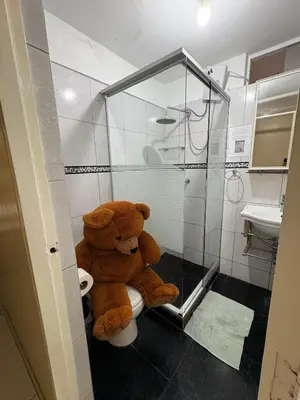 a large teddy bear sitting on a toilet in a bathroom at Departamento cerca al boulevard in Lima