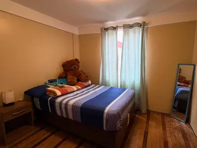 a teddy bear sitting on a bed in a bedroom at Departamento cerca al boulevard in Lima