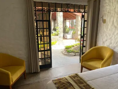 a bedroom with a bed and two chairs and an open door at Los Andes - Restaurant & Bungalows in Cieneguilla