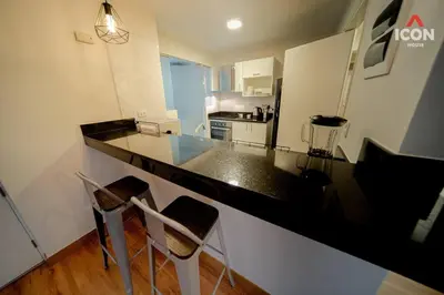 a kitchen with a black counter top and two chairs at Beautiful 2BR in Miraflores in Lima