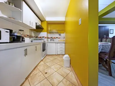 a kitchen with white cabinets and yellow walls at Killa Anqas - Departamento en el centro del Cusco in Cusco
