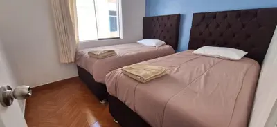two twin beds in a room with a window at Lucia's apartmens in Cusco