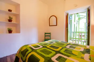 a bedroom with a bed with a green and yellow comforter at Dragonfly Hostels Cusco in Cusco