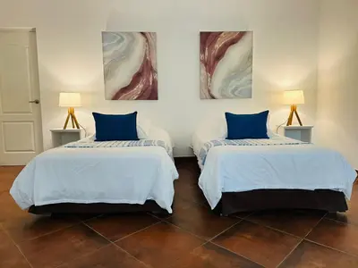 two beds with blue pillows in a room at Hotel Los Palomos in Lunahuaná