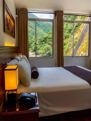 a bedroom with a large bed with a large window at Hotel Ferré Machu Picchu in Machu Picchu