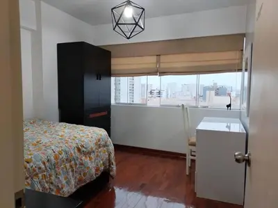 a bedroom with a bed and a desk and a window at Céntrico, acogedor y amplio apartamento en Magdalena in Lima