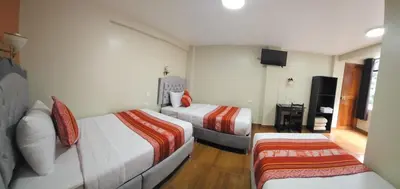 a hotel room with two beds and a flat screen tv at Hotel Horizonte in Machu Picchu