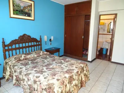 a bedroom with a bed and a blue wall at Hotel Nova in Lima