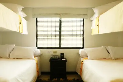 a bedroom with two beds and a window and a table at HOTEL RUSTICA SANTA EULALIA in Lima