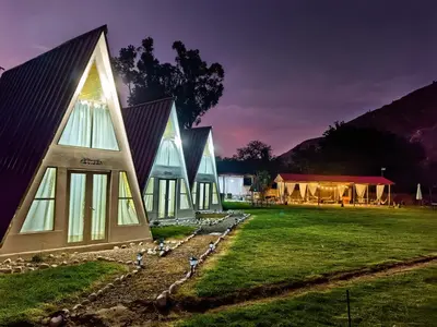 a house with a pointed roof on a grass field at Vallecito Lodge in Muyurina