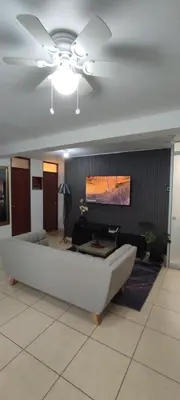 a living room with a couch and a ceiling fan at Sumaq Home Lima Airport in Lima