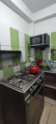 a kitchen with a stove with a red pot on it at Sumaq Home Lima Airport in Lima