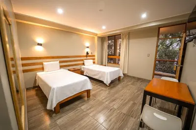 a hotel room with two beds and a desk at Hotel Fundo San Rafael in Nazca