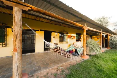 a person laying on a hammock in front of a house at Hotel Fundo San Rafael in Nazca