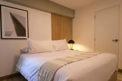 a bedroom with a large white bed with a lamp at One By Wynwood House in Lima
