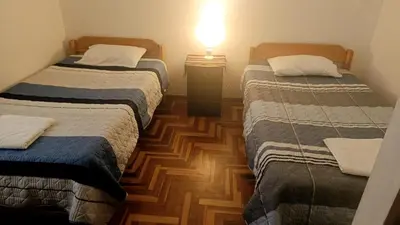 a room with two beds and a lamp on a wooden floor at WaskarWasi in Cusco