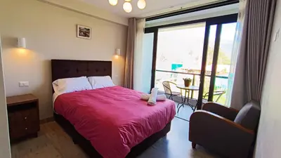 a bedroom with a bed with a red blanket and a window at PACHAMAMA APARTMENt in Urubamba