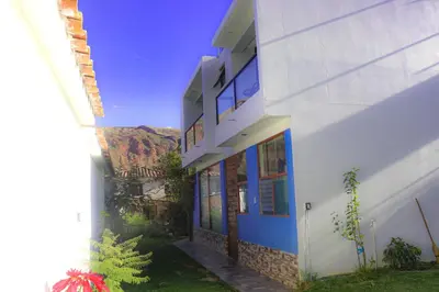 a white building with blue doors and a mountain in the background at PACHAMAMA APARTMENt in Urubamba