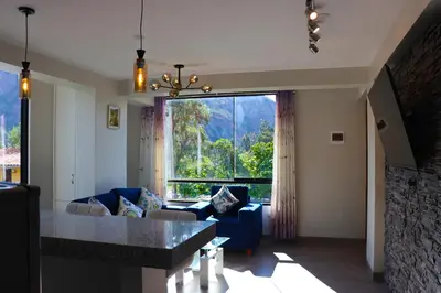 a living room with a blue couch and a large window at PACHAMAMA APARTMENt in Urubamba