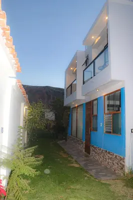 a white and blue house with a green yard at PACHAMAMA APARTMENt in Urubamba