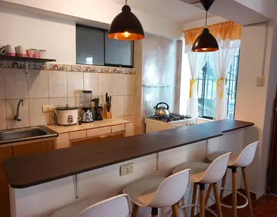 a kitchen with a counter with chairs around it at Cuesta del Inka in Cusco