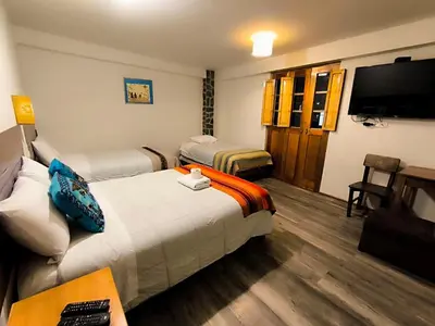 a hotel room with two beds and a flat screen tv at hostal Balcon de Piedra in Urubamba