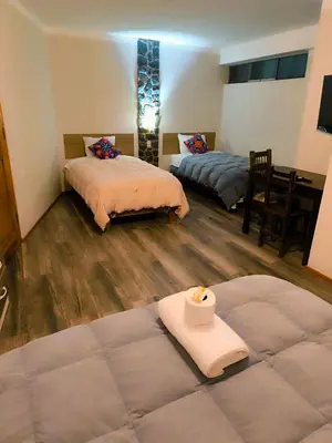 a room with two beds and a table with a candle at hostal Balcon de Piedra in Urubamba