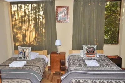 a room with two beds and a window with curtains at Hostal Goya Andina in Cusco