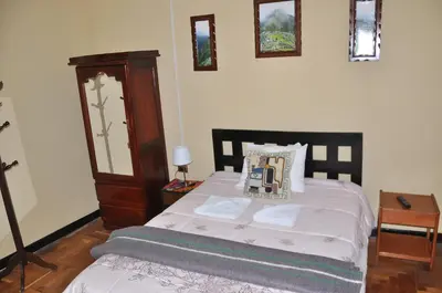a bedroom with a bed with a dresser and a table at Hostal Goya Andina in Cusco